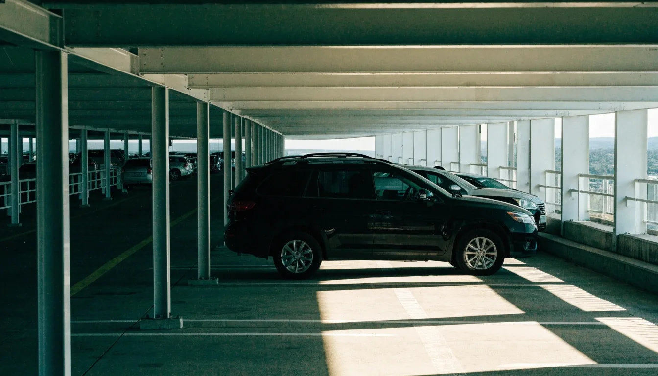 Upper level of an airport multi-storey car park with daylight falling across parked rows